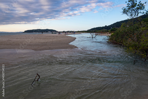 agua de rio invadido a ara da praia no pôr do sol  norte de Florianópolis, a Praia da Cachoeira do Bom Jesus, Ponta das Canas , SC Brasil  photo