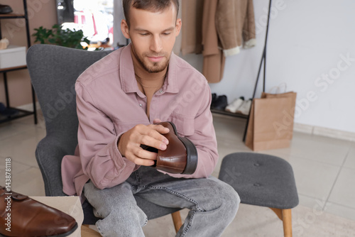 Young man with new shoes sitting in store