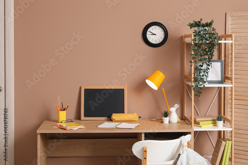Student's workplace with chalkboard, lamp and stationery in room