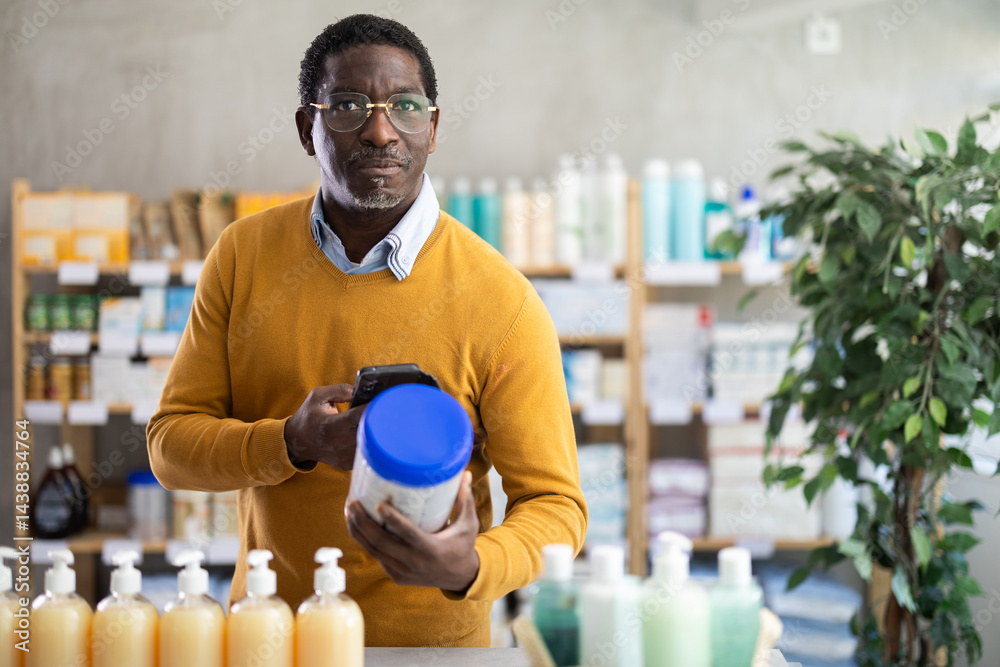African man in pharmacy scans QR code on infant food, studies item in detail, collects information online, uses quick link to access drugs instructions.