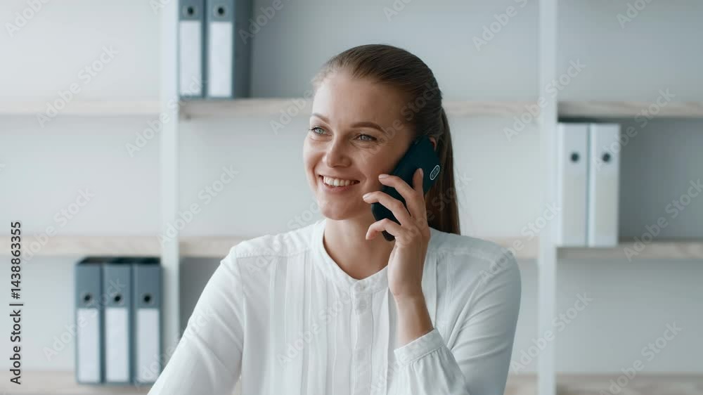 A young businesswoman is speaking on the phone while seated at a desk in a modern office. She appears focused and is dressed in smart attire, embodying a corporate lifestyle. A young businesswoman is speaking on the phone while seated at a desk in a modern office. She appears focused and is dressed in smart attire, embodying a corporate lifestyle.