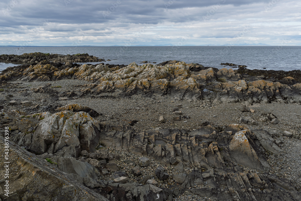 A rocky shoreline with a cloudy sky in the background A rocky shoreline with a cloudy sky in the background