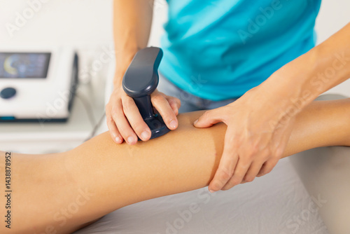 A physical therapist applies radiofrequency waves with a diathermy machine to relieve her patient's calf muscle pain