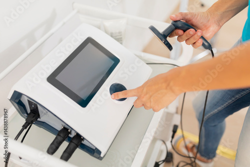 A physiotherapist sets up a diathermy and radiofrequency equipment to treat a patient's muscle pain