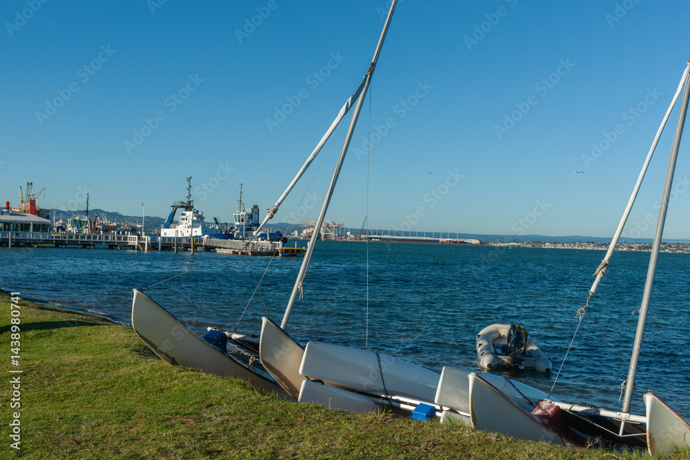 Catamarans and inflatable on shore with Port of Tauranga pilot boats and port facilities across Tauranga Harbour