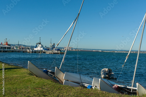Obraz na płótnie Catamarans and inflatable on shore with Port of Tauranga pilot boats and port facilities across Tauranga Harbour w salonie