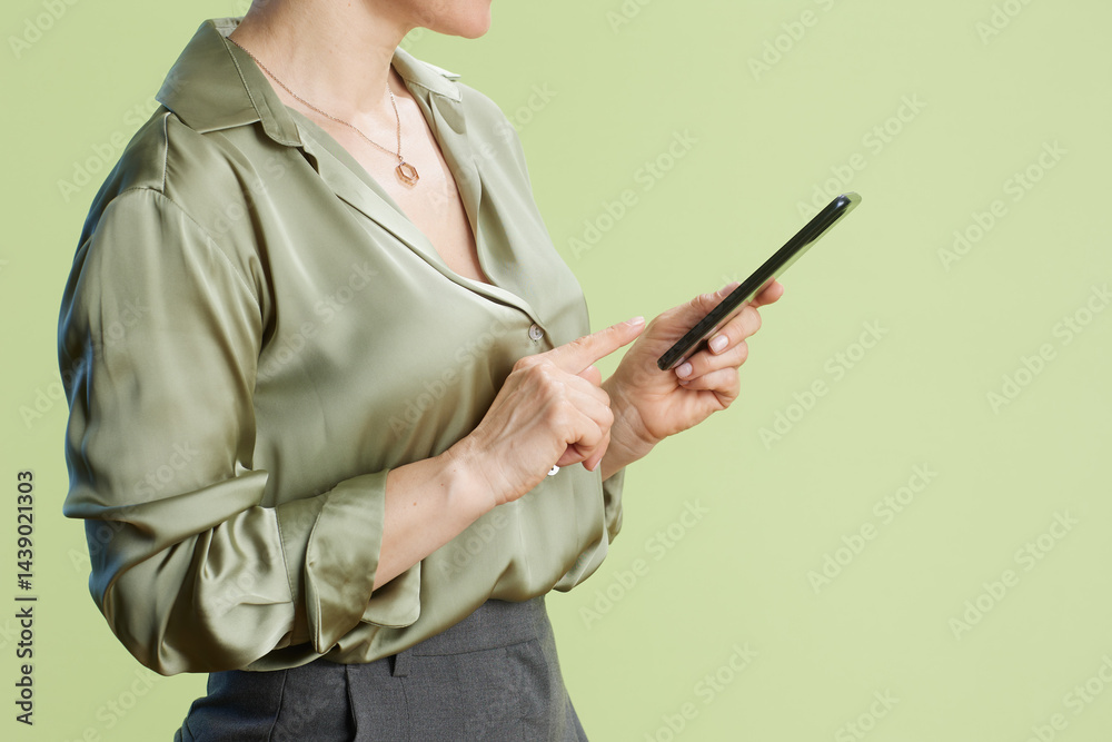 Professional woman tapping smartphone in studio setting