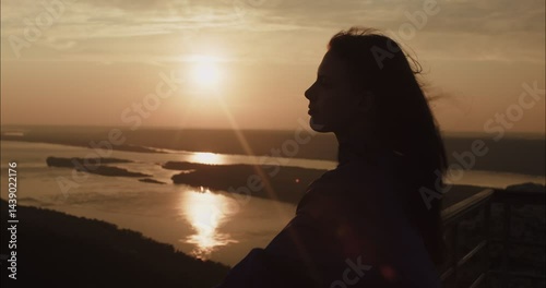 Woman watching sunset over river from mountain top