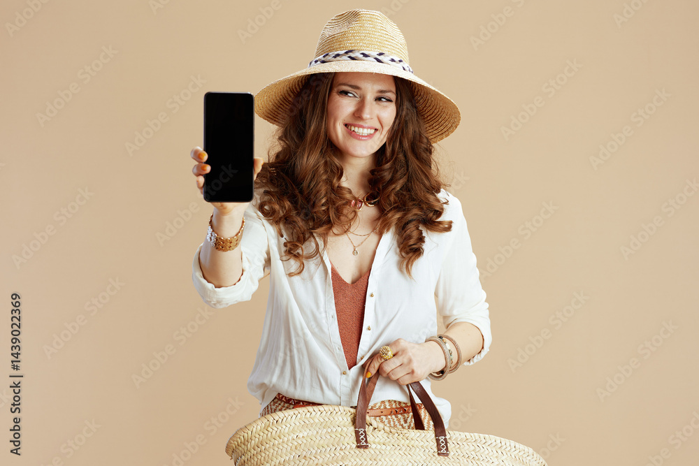 happy woman showing smartphone blank screen on beige