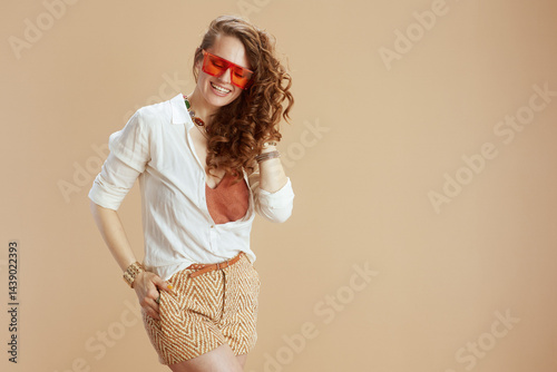 smiling trendy woman in blouse and shorts on beige