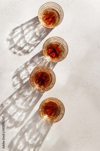 Obraz na płótnie Transparent alcohol Glasses with dark shadows at sunlight on beige table, top view minimal lifestyle, aesthetic flat lay shiny glass sparkling at sun, summer strong drink, copyspace, vertical w salonie
