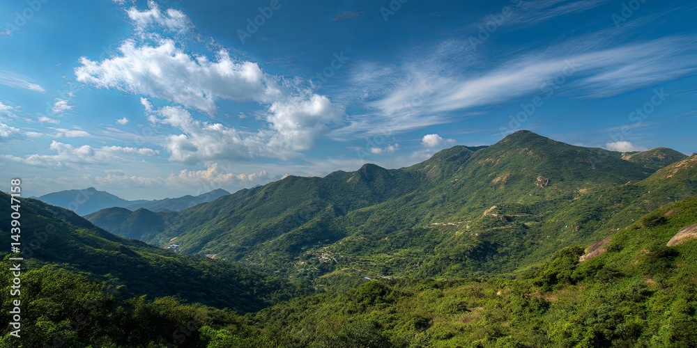 Fototapeta premium Breathtaking Scenic View of Lush Green Mountains Under Clear Blue Sky with Soft Clouds in Tranquil Natural Environment
