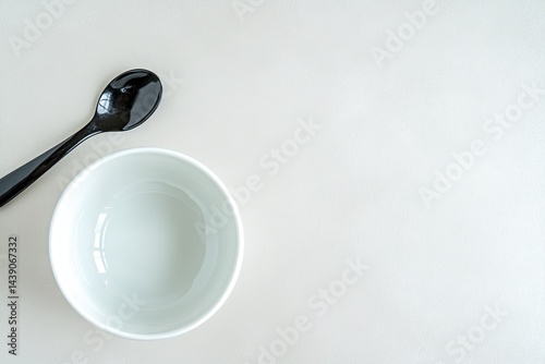 Empty white bowl and black spoon on light background photo