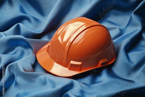 Bright orange safety helmet resting on a vibrant blue fabric surface. photo