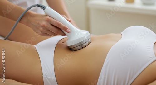 Woman Receiving Noninvasive Body Treatment with Handheld Device on Abdomen in White Two Piece Swimsuit