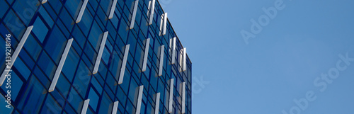 Contemporary glass facade of blue office building with geometric grid pattern, modern corporate architecture background for business and finance