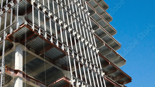Construction site showing modern building framework with exposed steel beams, metal support structures and industrial scaffolding