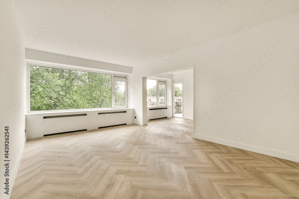 Obraz premium A spacious, bright interior featuring large windows that invite natural light, showcasing a stylish herringbone floor design in a minimalist setting.