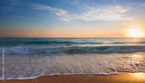 Waves gently wash onto a sandy beach at sunset, with golden sunlight reflecting on the water and clouds in the sky.