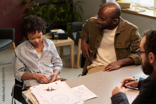 Obraz na płótnie Naughty African American boy sitting next to his father during discussion of his fight with classmates at psychological session w salonie