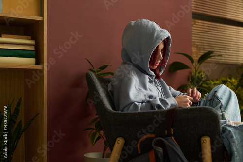 Obraz na płótnie Sad teenage girl in blue casual attire sitting in arm chair in psychologist office and sharing her problem during session w salonie