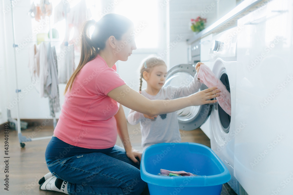 Obraz premium Mother and daughter doing laundry together in a bright home environment