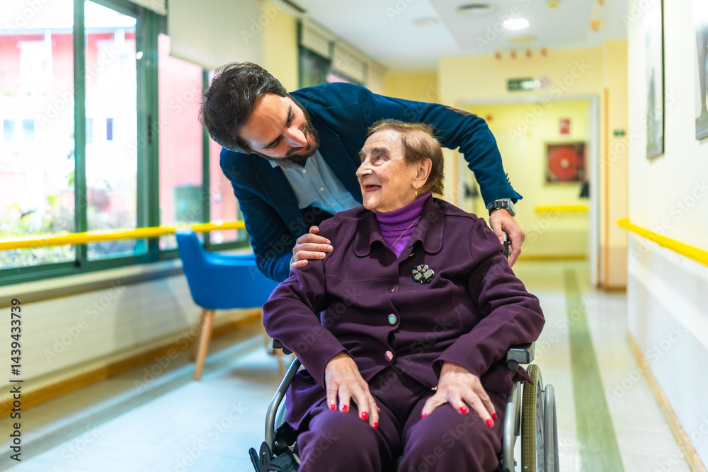 Male nurse assisting elderly woman in wheelchair at nursing home