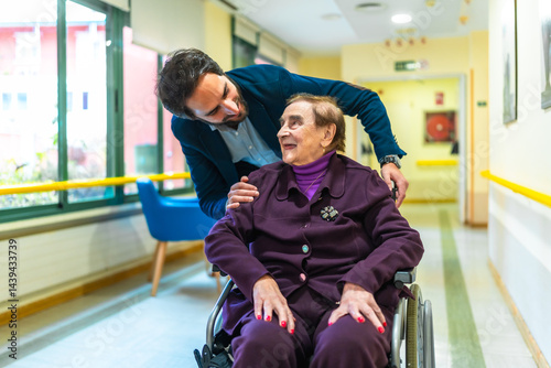 Obraz na płótnie Male nurse assisting elderly woman in wheelchair at nursing home w salonie