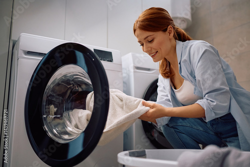 Quadro su tela Happy woman using washing machine in laundry room.