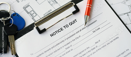 Pen and keys on Notice to quit form and planning blueprints of residential building project close up