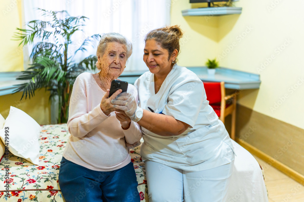 Nurse assisting elderly woman with smartphone in nursing home