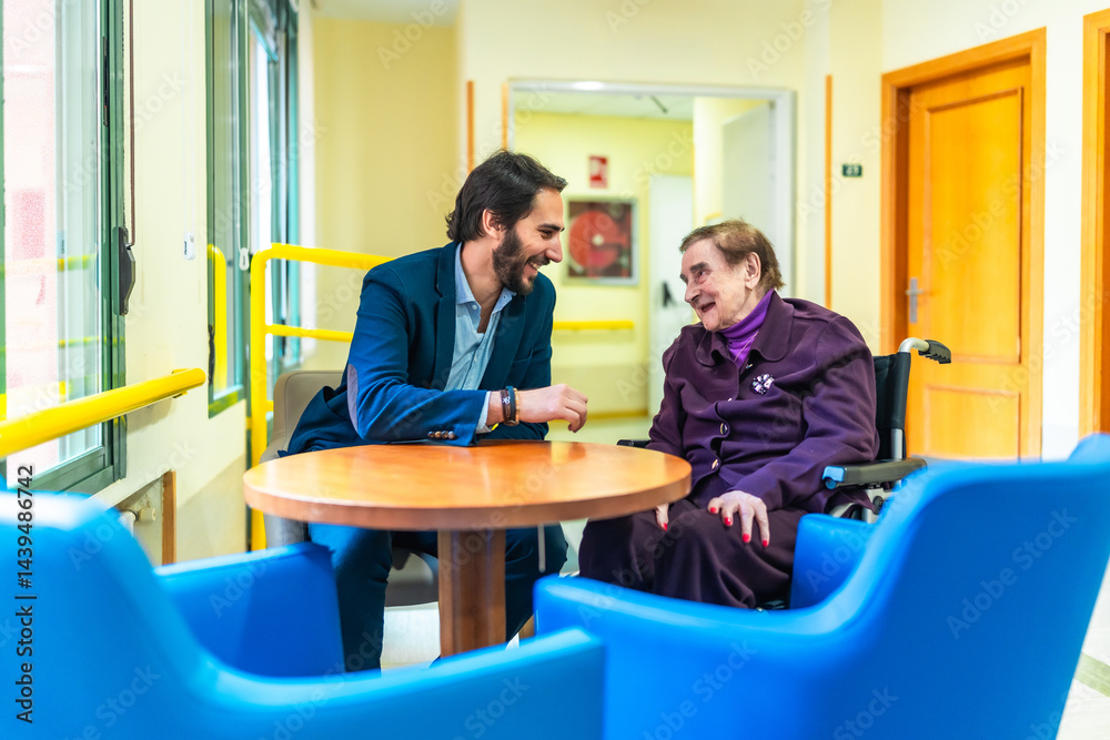 Manager chatting with elderly woman in wheelchair at nursing home