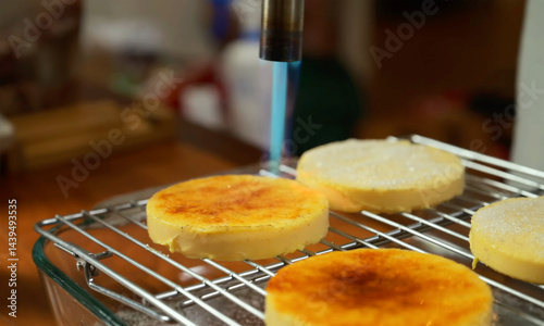 Obraz na plátně Close-up view of caramelizing crème brûlée with a kitchen torch, golden crisp sugar crust forming, homemade dessert preparation
