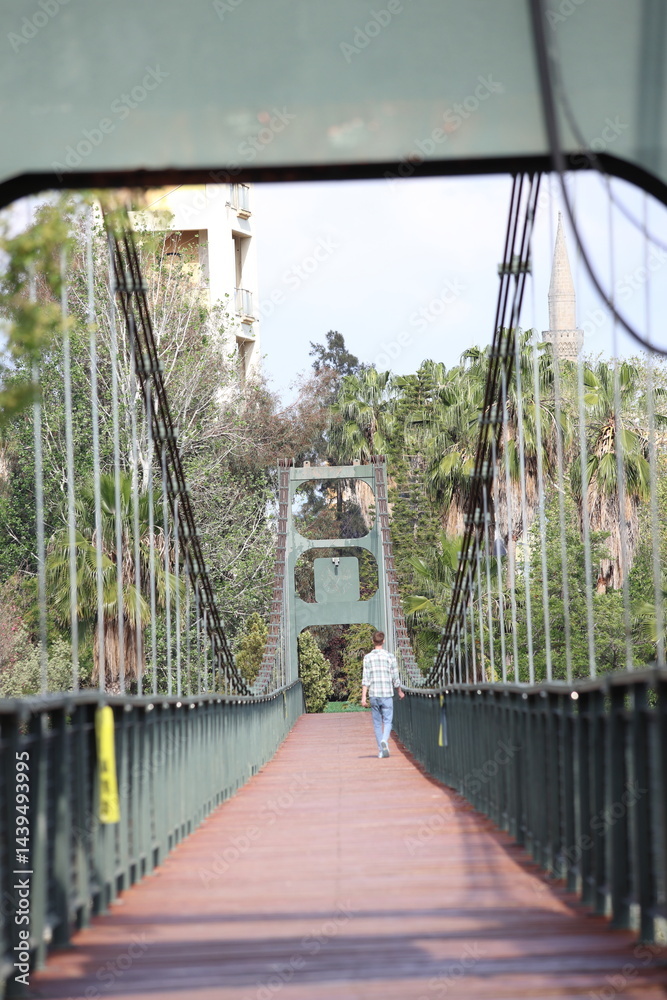 Fototapeta premium Rear view of a man walking on a suspension bridge