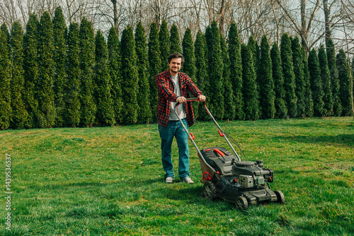 Man taking a break from lawn mowing in a suburban backyard during spring