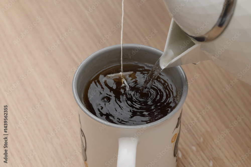Zbliżenie na herbatę ekspresowa w torebce zalewana wrzącą woda w porcelanowym kubku Zbliżenie na herbatę ekspresowa w torebce zalewana wrzącą woda w porcelanowym kubku