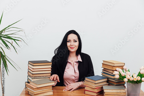 business woman teacher and stacks of educational books on table