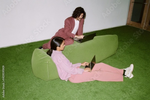 Two young business people, colleagues use laptops in modern office. Happy team working together, discussing solutions