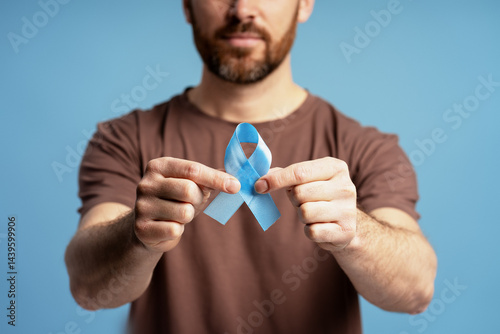Foto Man holding light blue ribbon for prostate cancer awareness