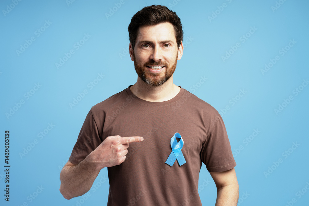 Man pointing at blue ribbon supporting prostate cancer awareness on blue background Man pointing at blue ribbon supporting prostate cancer awareness on blue background