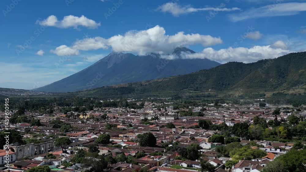 aerial view of antigua guatemala with red shingle rooftops and volcanoes agua fuego and acatenango peaks in the clouds on bright sunny day (volcano mountain travel tourism hiking destination) latin