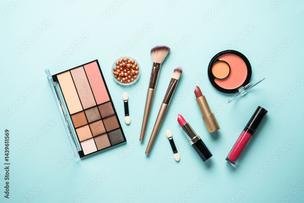 Beauty products on blue background. Cosmetic palette, brushes and lipsticks. Top view.