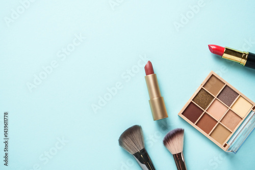 Obraz na płótnie Beauty products on blue background. Cosmetic palette, brushes and lipsticks. Top view. w salonie