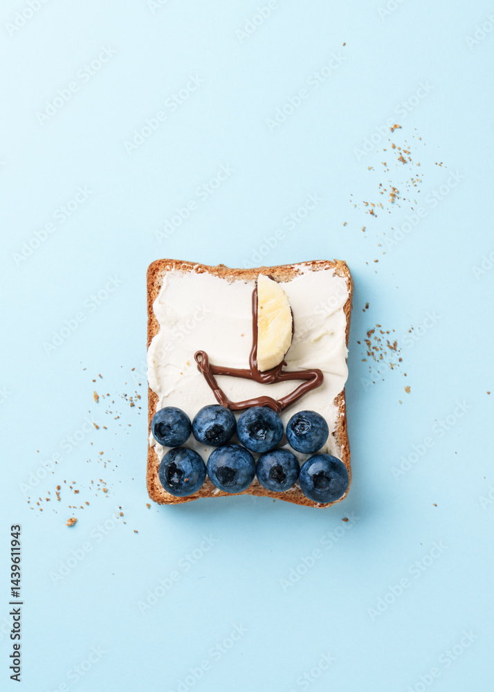 Open sandwich with funny pictures on it. Toast with blueberry and chocolate paste.