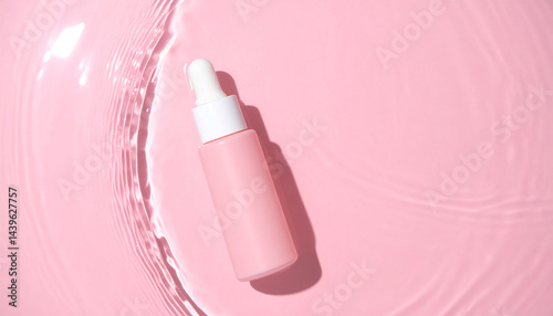 Moisturizing serum for the skin stands in the water on a pink background.