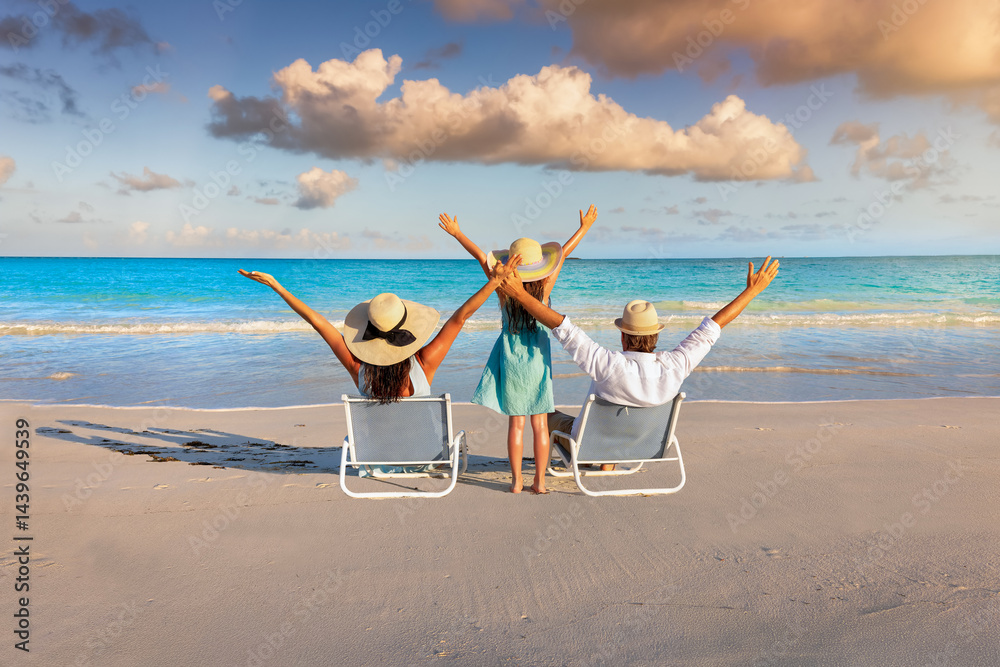 A happy family on summer holidays sits on a tropical beach and enjoys together the beautiful sunset
