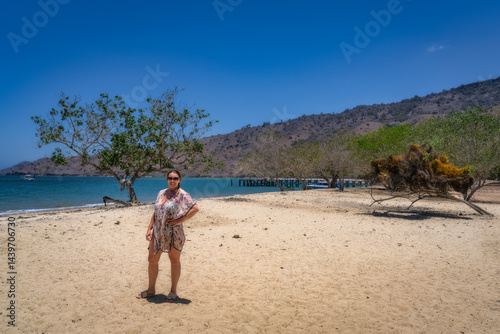 Papier peint A woman stands confidently on a pristine sandy beach of Komodo Island, surrounde