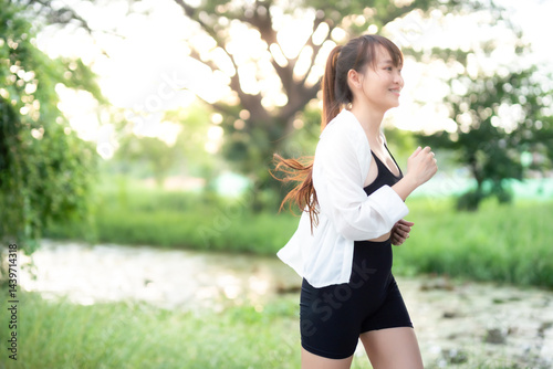 Obraz na płótnie Portrait of beautiful asian Young woman in white robe wearing sportswear jogging working out outside. training on public equipment in outdoor at park. concept Exercise Healthy lifestyle. w salonie