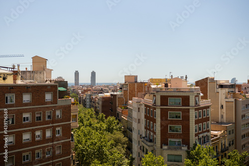 Cityscape with rows of residential buildings leading towards the distant sea under clear sky in Barcelona