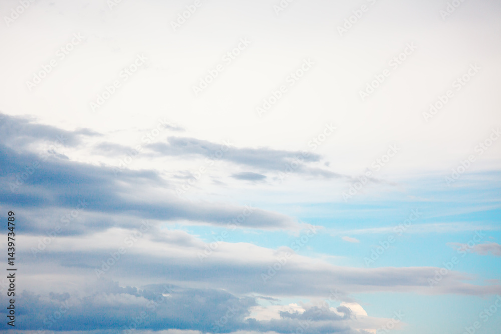 Serene sky with gentle gradient of colors transitioning from soft whites at the top to deep blues below. Wispy clouds stretch across the expanse, varying in texture and density